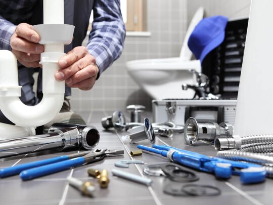 Photo of Utah plumber surrounded by pipes and tools