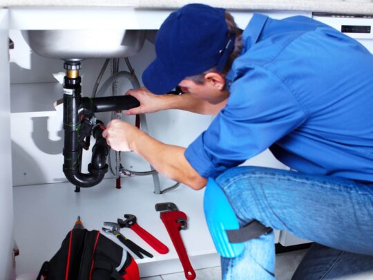 Photo of Utah plumber working under a sink on p-trap